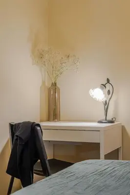 a desk with a vase of flowers and a lamp on it at Canela Homes BARCELONA SANT PAU in Barcelona