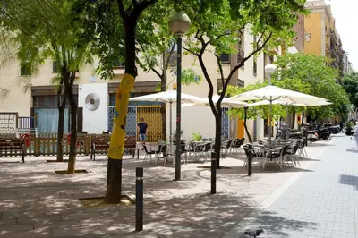 a street with tables and chairs and umbrellas at Gracia Travesera 2 Bedrooms Renovated Apartment in Barcelona