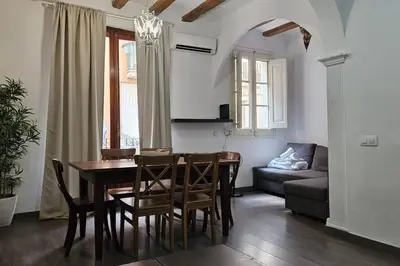 a dining room and living room with a table and chairs at Romantic 19th century apartment in Barcelona