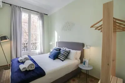 a bedroom with a bed with blue pillows and a window at Passeig Sant Joan in Barcelona