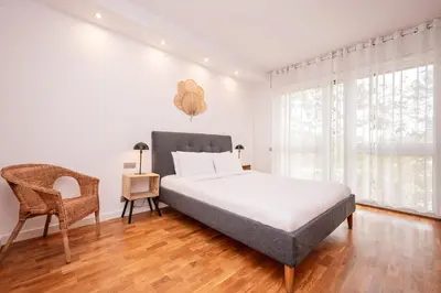 a white bedroom with a bed and a chair at Sweett - Nova Icaria Beach in Barcelona