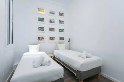 two beds in a white room with pictures on the wall at Canela Homes BARCELONA VALÈNCIA in Barcelona