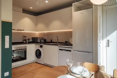 a kitchen with white cabinets and a table with a sink at Casa Morera in Barcelona