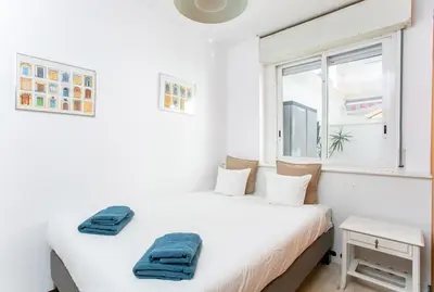 two beds in a white room with a window at Canela Homes BARCELONA MONUMENTAL in Barcelona