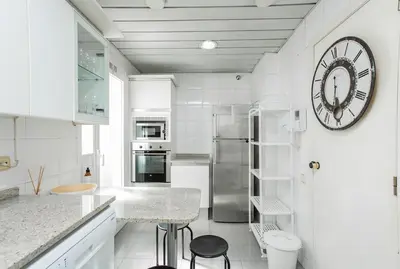 a white kitchen with a large clock on the wall at Canela Homes BARCELONA MONUMENTAL in Barcelona