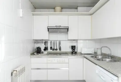 a white kitchen with white cabinets and a sink at Canela Homes BARCELONA MONUMENTAL in Barcelona