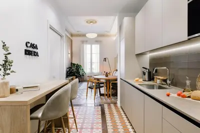 a kitchen with white cabinets and a table with chairs at Casa Ribera in Barcelona