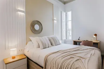 a white bedroom with a bed and a mirror at Casa Ribera in Barcelona