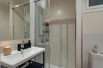 a white bathroom with a sink and a shower at Casa Tamarita in Barcelona