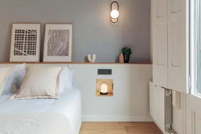a white bedroom with a bed and a shelf at Casa Atlas in Barcelona