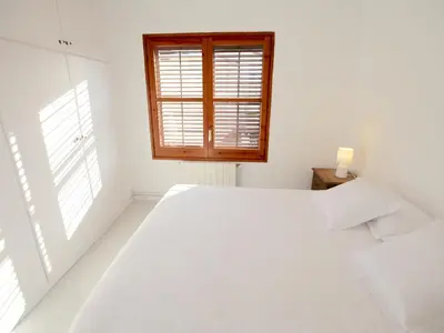 a white bedroom with a large bed and a window at Apartamento nuevo muy luminoso in La Crehueta