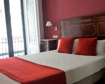 a bedroom with a large bed with red pillows at Hotel Noucentista in Sitges