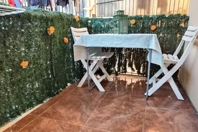 a table and two chairs sitting next to a hedge at Apartamento Gran Via para 6 en el centro de Premià in Premiá de Mar