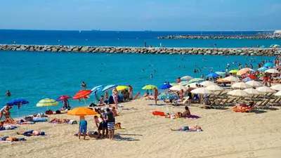 a crowd of people on a beach with umbrellas at Apartamento Gran Via para 6 en el centro de Premià in Premiá de Mar