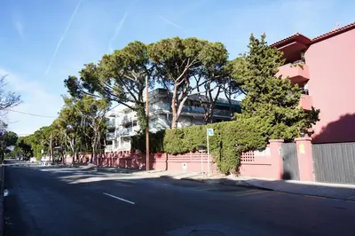 an empty street with trees and a pink building at Apartment-4people-Parking-Castelledefels-Bikes-Bbq in Castelldefels