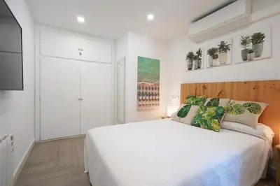 a white bedroom with a large bed and a tv at Apartment-4people-Parking-Castelledefels-Bikes-Bbq in Castelldefels