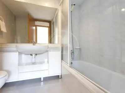 a white bedroom with a bed and a window at Apartamento cerca de la playa in Barcelona