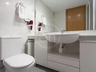 a white bathroom with a toilet and a sink at Apartamento cerca de la playa in Barcelona