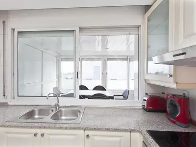 a kitchen with white cabinets and a white refrigerator at Apartamento cerca de la playa in Barcelona