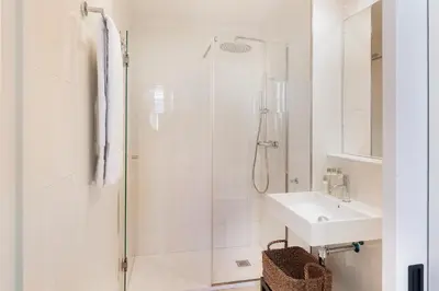 a white bathroom with a shower and a sink at Casa Mercader - Simaba Group in Barcelona