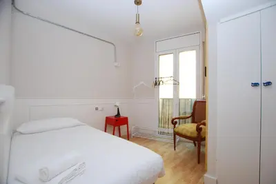 a white bedroom with a bed and a chair at Masnou Chill in Masnou