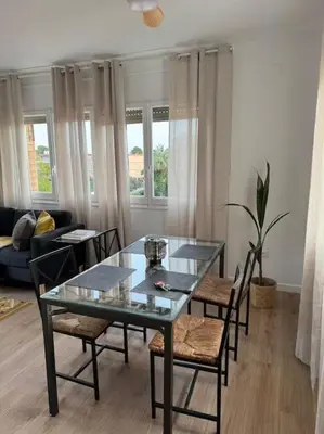 a living room with a glass table and chairs at Ático gran terraza cerca BCN in Castelldefels
