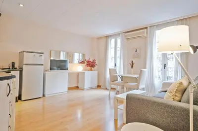 a living room with a couch and a table and a kitchen at Winahost Barcelona Provenza in Barcelona