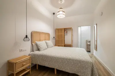a small bedroom with a bed and a night stand at El Niu Apartamentos con terraza Camp Nou in Hospitalet de Llobregat