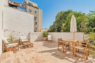 a patio with a table and chairs and an umbrella at El Niu Apartamentos con terraza Camp Nou in Hospitalet de Llobregat