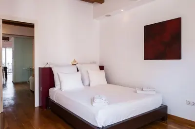 a bedroom with a white bed with a clock on it at Moderno y auténtico en el corazón de Poble Sec in Barcelona