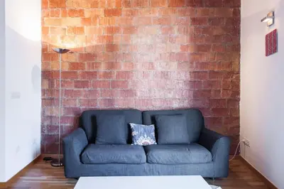 a blue couch in front of a brick wall at Moderno y auténtico en el corazón de Poble Sec in Barcelona