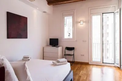 a white bedroom with a bed and a tv at Moderno y auténtico en el corazón de Poble Sec in Barcelona
