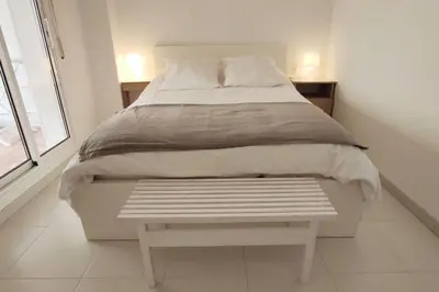 a white bed with a bench in a bedroom at Espacioso con patio interior in Sabadell