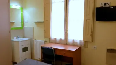 a small bathroom with a desk and a window at Hostal Capitol Ramblas in Barcelona
