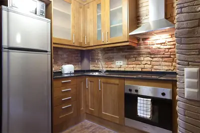 a kitchen with wooden cabinets and a white refrigerator at El Born - Barcelona Center Apartment in Barcelona