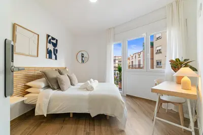 a white bedroom with a large bed and a desk at Livinn House - Self Check in in Hospitalet de Llobregat