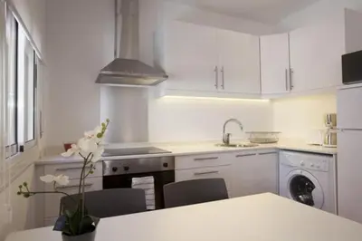 a kitchen with white cabinets and a table with a flower at Barceloneta near Beach Apartments in Barcelona
