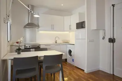 a kitchen with white cabinets and a table and chairs at Barceloneta near Beach Apartments in Barcelona