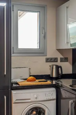 a kitchen with a washing machine and a window at Canela Homes BARCELONA FÒRUM in Sant Adria de Besos