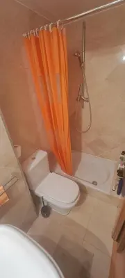 a bathroom with an orange shower curtain and a toilet at Lovely Room near Park Guell in Barcelona