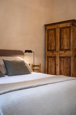 a bedroom with a bed and a wooden door at Mas Grimosach - Masía en finca y bodega ecológica - Adults Only in Sant Pau dʼOrdal