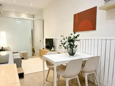 a white dining room with a vase of flowers on a table at Eixample Apart Sagrada Familia 52 in Barcelona