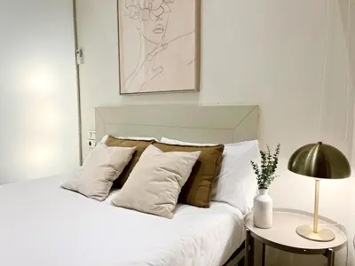 a white bed with pillows and a table with a lamp at Eixample Apart Sagrada Familia 52 in Barcelona