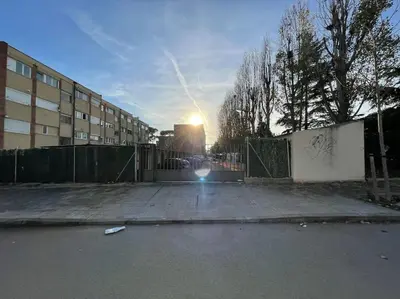 a sun setting behind a fence in a parking lot at Apto en la playa a 20 min en tren de Barcelona in Cabrera de Mar