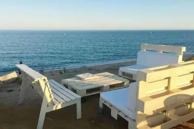 a picnic table and chairs on the beach with the ocean at Apto en la playa a 20 min en tren de Barcelona in Cabrera de Mar
