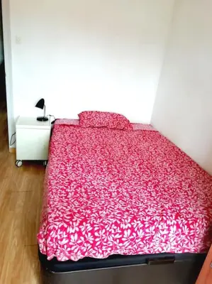 a bed in a room with a red comforter at Habitación doble exterior en piso compartido in Sant Cugat del Vallès
