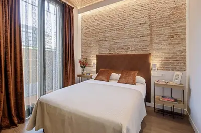 a bedroom with a white bed and a brick wall at Pau Claris Double - Home next to Paseo de Gracia in Barcelona