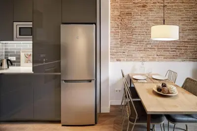 a kitchen with a stainless steel refrigerator and a table at Pau Claris Double - Home next to Paseo de Gracia in Barcelona