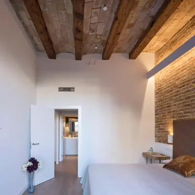 a bedroom with a white bed and a brick wall at Pau Claris - Design apt next to Paseo de Gracia in Barcelona