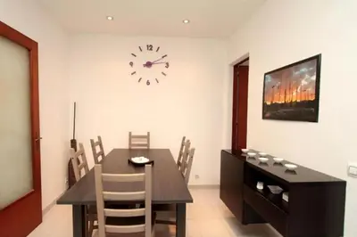 a dining room with a table and a clock on the wall at Modern pad in a great old barrio in Barcelona